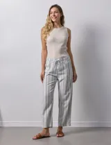 Pantalón de lino a rayas verticales grises y blancas, con pretina elastizada, lazo de ajuste y bolsillos delanteros y traseros.