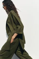 Blazer color verde oliva confeccionada en lino, con cuello solapa, manga tres cuartos con vuelta y cierre cruzado con botones.