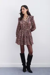 Vestido corto color marrón con estampado de cebra, escote en V, mangas largas con volados en los hombros y puños elásticos con volados.
