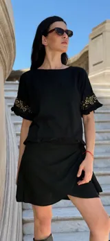 Remera negra de corte holgado con mangas cortas con volados y detalle de apliques de piedras en los volados.