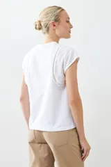 Remera blanca de algodón con cuello redondo y mangas cortas con detalle de broderie y vainillas.