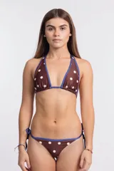 Top de bikini estilo triángulo con estampado de lunares blancos sobre fondo marrón. Presenta ribetes en color azul y se ata al cuello y a la espalda.