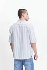 Camisa de manga corta con corte oversize, a rayas verticales blancas y grises, con cuello clásico y cierre frontal con botones. Confeccionada en algodón.