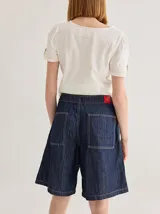 Bermuda color marrón claro, de tiro medio/alto, calce cómodo y relajado, con detalle de voladito en bolsillos.