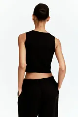 Chaleco negro entallado de punto suave, con cuello redondo y botones metálicos plateados en el frente.
