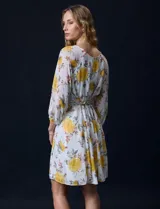 Vestido corto de gasa estampada con flores amarillas, marca Sandra Darren. Tiene escote redondo, mangas 3/4 con puño elastizado y lazo de ajuste en la cintura.