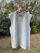 Musculosa verde oliva de algodón con cuello redondo y sisas amplias. Estampado frontal con tres hojas blancas. Diseño unisex y corte holgado.