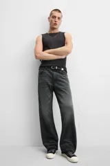 Pantalón de jean negro con efecto lavado, corte flare, cinco bolsillos, cierre frontal con cremallera y botón, y bajo con acabado irregular.