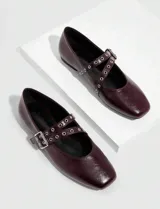 Balerinas color borgoña con puntera cuadrada y tira cruzada con hebilla y ojales metálicos.