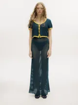 Top tejido calado color azul petróleo con cuello en V y botones carey. Tiene mangas cortas y puños en color amarillo contrastante.