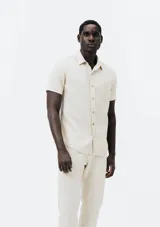 Camisa celeste de manga corta con cuello clásico, cierre frontal con botones y bolsillo de parche en el pecho. Corte recto.