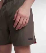 Bermuda deportiva masculina color marrón, con cintura elástica, cordón para ajuste, bolsillos, textura, etiqueta aplicada en la barra y reflectivos laterales.