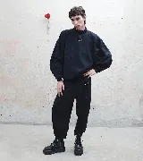 Pantalón sastre corte babucha color negro, con tablas, detalle de argolla metálica delantera y trasera, y tiro alto.