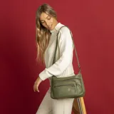 Bandolera color beige de símil cuero con dos bolsillos frontales con cierre, doble apertura superior con cierre, un bolsillo trasero con cierre y dos bolsillos internos. Incluye correa de galón larga regulable para llevar al hombro.