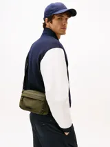 Cartera bandolera Tommy Hilfiger color verde militar, con correa ajustable negra, bolsillo frontal con cierre y logo de la marca en el frente.