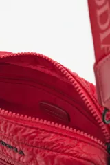 Bandolera negra de nylon matelassé con correa regulable, avíos metálicos, llavero de corazón y dijes desmontables.