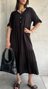 Vestido midi negro con botones frontales, mangas cortas con volados y falda con volados escalonados.