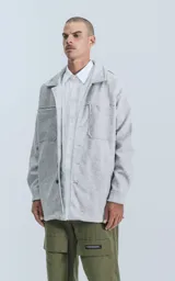 Campera gris melange de paño con cuello camisero, cierre frontal con botones a presión, bolsillos frontales y corte recto.