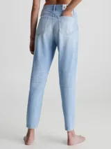 Jeans celeste claro de corte mom, con roturas en las rodillas, tiro alto, cinco bolsillos y cierre con botón y cremallera.