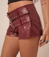 Micro short de cuero sintético color borgoña, con múltiples cinturones con hebillas metálicas y ojales.