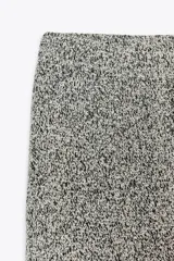 Pantalón gris jaspeado de tejido bouclé, tiro alto, cintura elástica y pierna ancha.