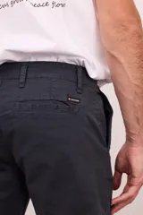 Bermuda de gabardina color verde oliva, con bolsillos laterales y traseros. Cierre frontal con botón y cremallera.