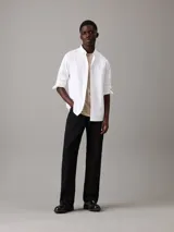 Camisa blanca de corte regular, confeccionada en tejido oxford de algodón y elastano. Tiene mangas largas con puños abotonados, cierre frontal con botones y cuello clásico. Incluye etiqueta con el logo de Calvin Klein.