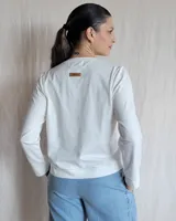 Remera blanca de mangas largas con cuello en V y costuras a la vista.