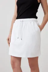 Minifalda blanca de corte recto, con pretina elastizada con cordón ajustable y bolsillos laterales.