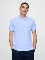 Chomba celeste de piqué con cuello clásico y tapeta de dos botones. Tiene mangas cortas con puños acanalados y logo de un oso bordado en el pecho.