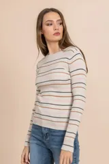 Camiseta tejida rib color beige con rayas horizontales en negro, rosa y marrón. Es de manga larga y cuello redondo.