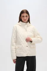 Campera blanca con diseño acolchado, cierre frontal con botones a presión y capucha desmontable.