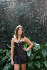 Vestido corto negro con estampado floral, escote halter con argolla, top strapless con breteles finos que se atan al cuello, cut-outs en la cintura y falda con volados.