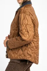 Campera capitoneada de color marrón con diseño de flores pespunteadas, cuello camisero en contraste oscuro y cierre frontal de cremallera.