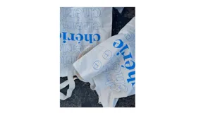 Bolsa de tela reutilizable color blanco crudo, con asas de tela y estampado repetitivo en azul de la palabra "Chéri" en tipografía serif y un logo circular estilizado.