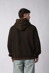 Buzo canguro negro con capucha, calce oversize, confeccionado en frisa 100% algodón con lavado gastado y aplique cosido en el pecho.