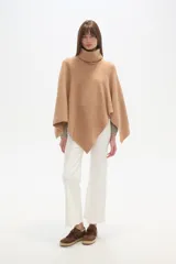 Poncho tejido color tostado, con cuello alto tipo tortuga y diseño asimétrico en el ruedo.