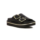 Sandalias planas negras con plataforma gruesa y dos tiras anchas ajustables con hebillas cuadradas doradas. La plataforma tiene un detalle de línea dorada.