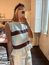 Chaleco de punto a rayas horizontales en tonos celeste, marrón y beige, con cuello redondo y volados en el ruedo.