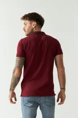 Remera polo negra de manga corta con cuello clásico, cierre de botones, bolsillo en el pecho y logo estampado.