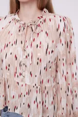 Blusa con estampado multicolor, de corte holgado y mangas largas, con detalle de lazo en el cuello.
