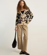 Cardigan largo de punto color beige con estampado floral negro, escote en V y cierre abotonado.
