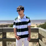 Chomba tejida de corte oversize con rayas horizontales verdes oscuras y blancas, cuello tipo polo blanco y mangas cortas.