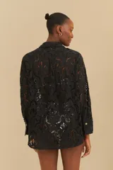 Camisa negra de encaje con cuello clásico, cierre frontal con botones y mangas largas.