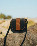 Bandolera de cuero color marrón con correa larga regulable, solapa con diseño trenzado y cierre con broche imantado.