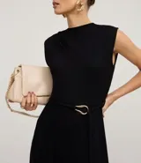 Mono negro sin mangas, con cuello redondo y cierre tipo gota en la espalda. Presenta hombreras marcadas, cintura ajustable con cinturón de lazo y hebilla metálica irregular, y pantalón ancho de pierna acampanada.