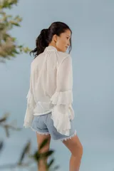 Blusa color rosa pálido de tejido fresco y liviano, con cuello alto con lazo y mangas largas con volados.