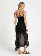 Vestido midi negro de lurex con breteles finos, corte ajustado y falda asimétrica con volados. Incluye cinturón de soga con hebilla dorada.