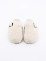 Pantuflas cerradas color crema, forradas en piel sintética con hebilla decorativa.