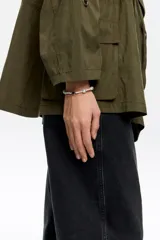 Pulsera doble con una hilera de perlas y otra de cadena dorada. Incluye un dije redondo con un corazón esmaltado y un dije de corazón liso.